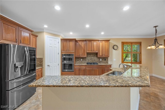 kitchen with a large island with sink, an inviting chandelier, hanging light fixtures, sink, and stainless steel appliances