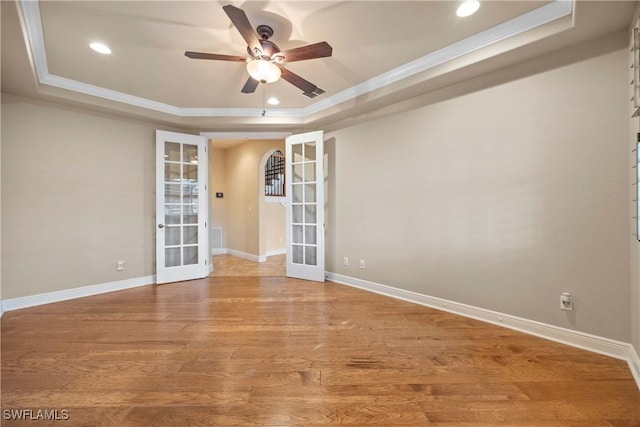 spare room with hardwood / wood-style floors, ceiling fan, a raised ceiling, and french doors