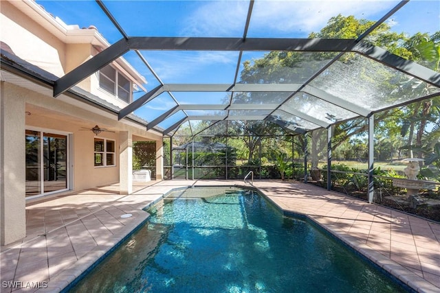 view of pool with glass enclosure, ceiling fan, and a patio area