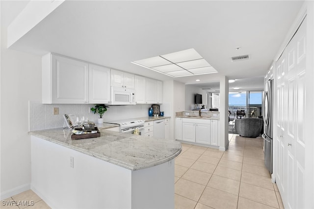 kitchen featuring white cabinets, light stone countertops, white appliances, and kitchen peninsula