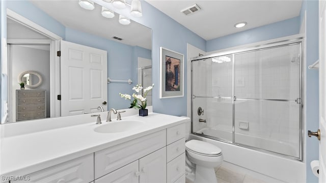 full bathroom featuring toilet, vanity, tile patterned floors, and bath / shower combo with glass door