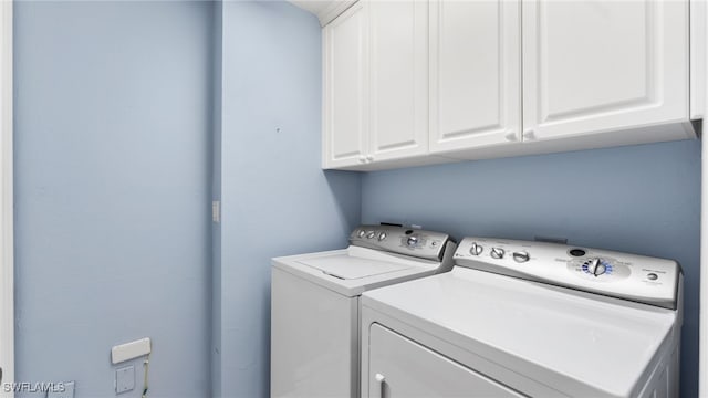 clothes washing area featuring cabinets and washing machine and clothes dryer