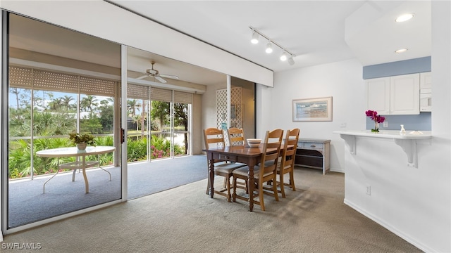 dining space featuring light carpet, track lighting, and ceiling fan