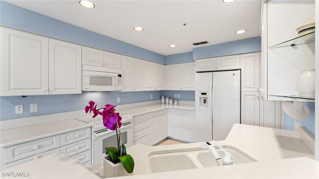 kitchen with white cabinetry, sink, and white appliances