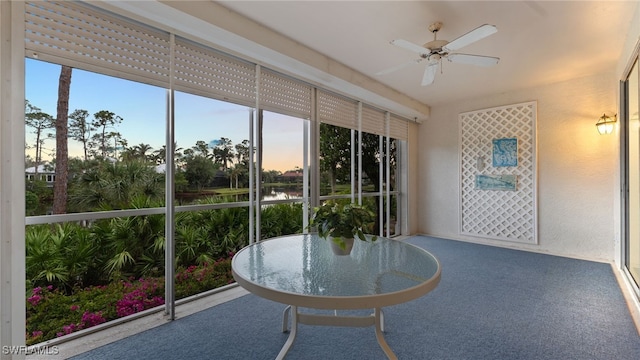 sunroom / solarium with a water view, ceiling fan, and a healthy amount of sunlight