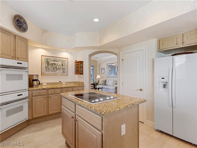 kitchen with a center island, light hardwood / wood-style floors, white appliances, and light brown cabinets