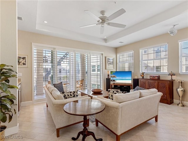 living room featuring ceiling fan and a tray ceiling