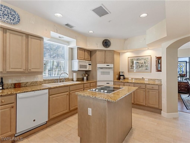 kitchen featuring light brown cabinets, white appliances, a kitchen island, and sink