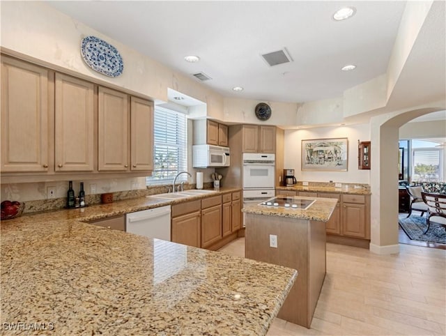 kitchen featuring white appliances, a center island, a healthy amount of sunlight, and sink