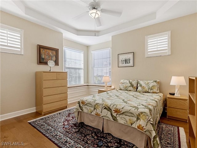 bedroom with hardwood / wood-style floors, a raised ceiling, and ceiling fan