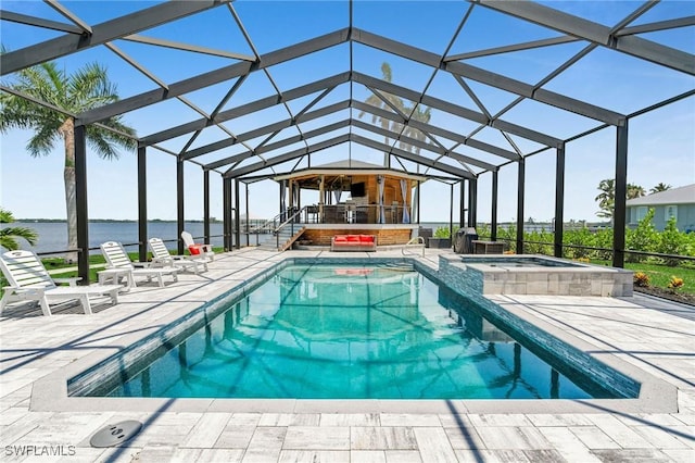 view of swimming pool featuring glass enclosure, a water view, an in ground hot tub, and a patio