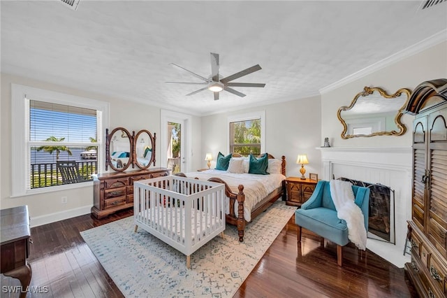 bedroom featuring ceiling fan, dark hardwood / wood-style flooring, ornamental molding, and a brick fireplace