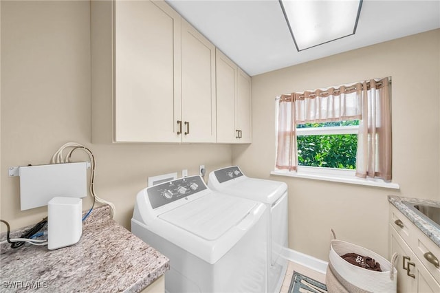 clothes washing area featuring cabinets and separate washer and dryer