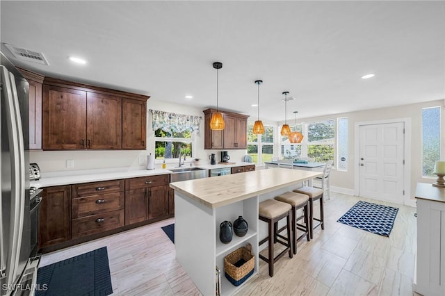 kitchen featuring dark brown cabinetry, a breakfast bar, a center island, and decorative light fixtures