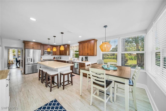 kitchen with pendant lighting, a center island, a healthy amount of sunlight, and stainless steel appliances