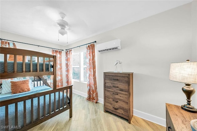 bedroom featuring ceiling fan, light hardwood / wood-style floors, and a wall mounted air conditioner