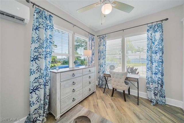 home office featuring light wood-type flooring, a wall unit AC, and ceiling fan