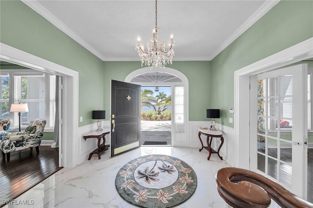 entrance foyer with ornamental molding, light hardwood / wood-style flooring, a healthy amount of sunlight, and a notable chandelier