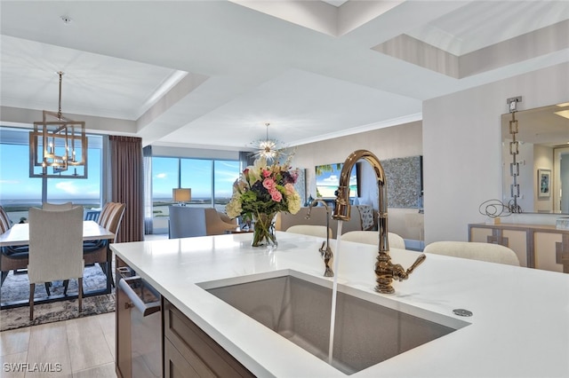 kitchen featuring pendant lighting, sink, a chandelier, stainless steel dishwasher, and a tray ceiling