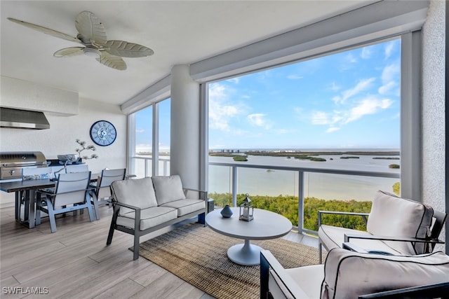 sunroom / solarium featuring a water view, ceiling fan, and a healthy amount of sunlight