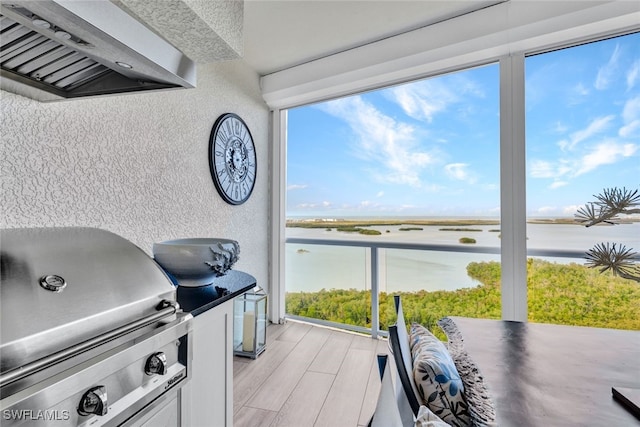 view of patio / terrace with a water view, a grill, and an outdoor kitchen