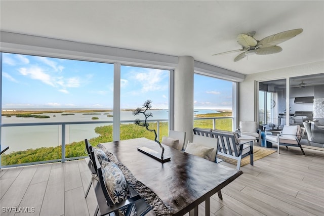 sunroom with a water view and ceiling fan