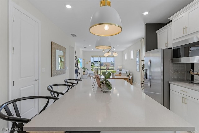 kitchen featuring white cabinets, stainless steel microwave, and a spacious island