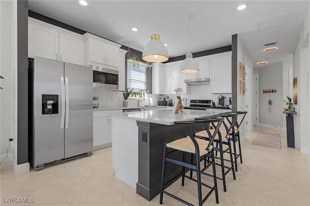 kitchen featuring tasteful backsplash, decorative light fixtures, a kitchen island, white cabinetry, and stainless steel appliances