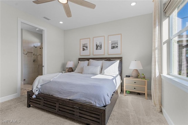 bedroom with multiple windows, connected bathroom, light colored carpet, and ceiling fan