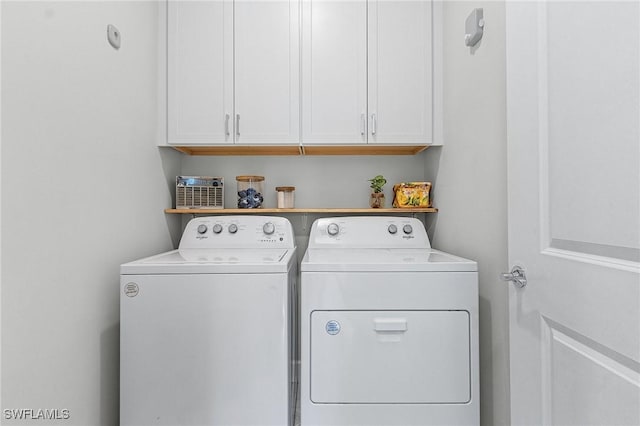 clothes washing area with cabinets and washer and dryer