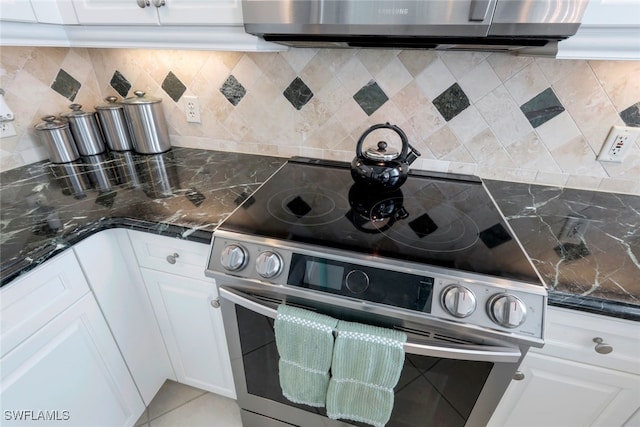 kitchen featuring white cabinets, backsplash, stainless steel appliances, and dark stone counters