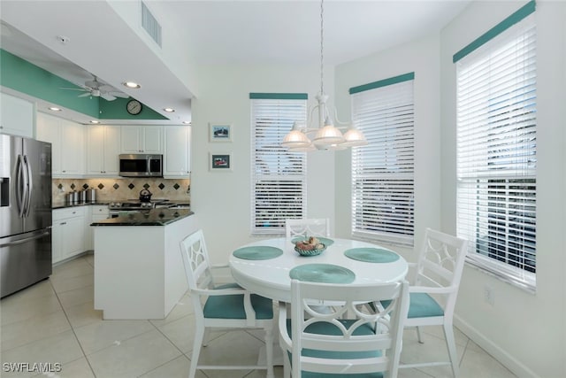 dining area with light tile patterned floors and ceiling fan with notable chandelier