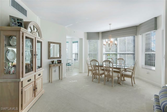 dining area featuring light colored carpet and an inviting chandelier