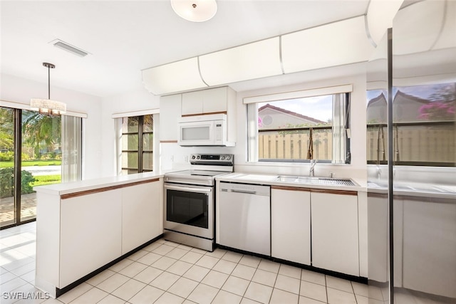 kitchen featuring decorative light fixtures, white cabinetry, white appliances, and a healthy amount of sunlight