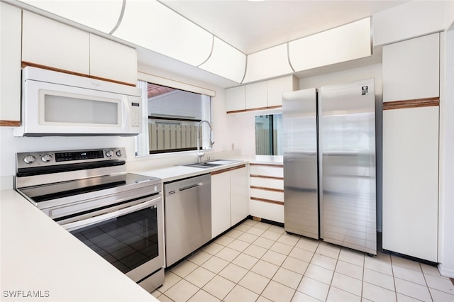 kitchen with white cabinets, light tile patterned flooring, sink, and stainless steel appliances