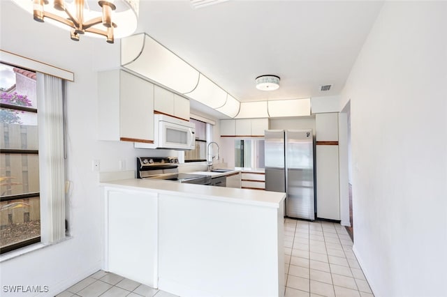 kitchen featuring sink, stainless steel appliances, light tile patterned floors, kitchen peninsula, and white cabinets