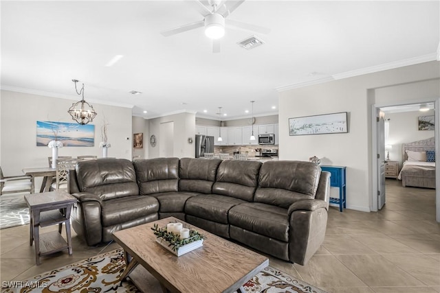 tiled living room with ceiling fan with notable chandelier and ornamental molding