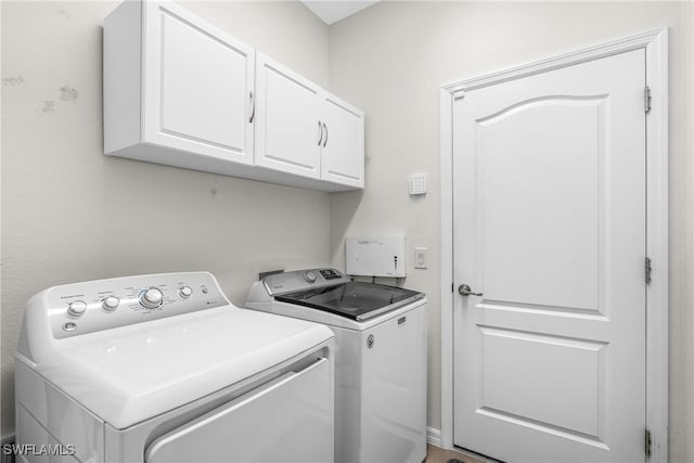 clothes washing area featuring separate washer and dryer and cabinets