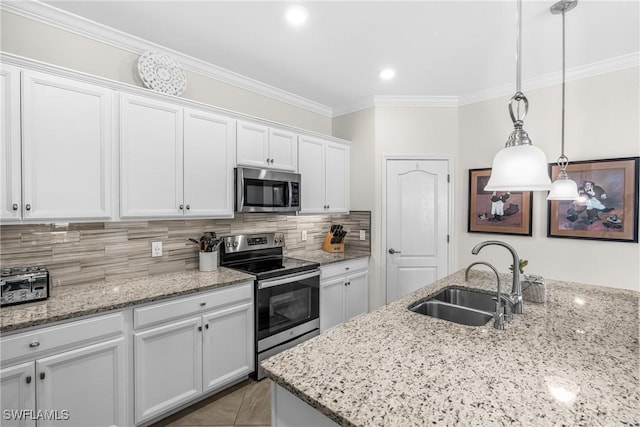 kitchen with pendant lighting, backsplash, white cabinets, sink, and appliances with stainless steel finishes