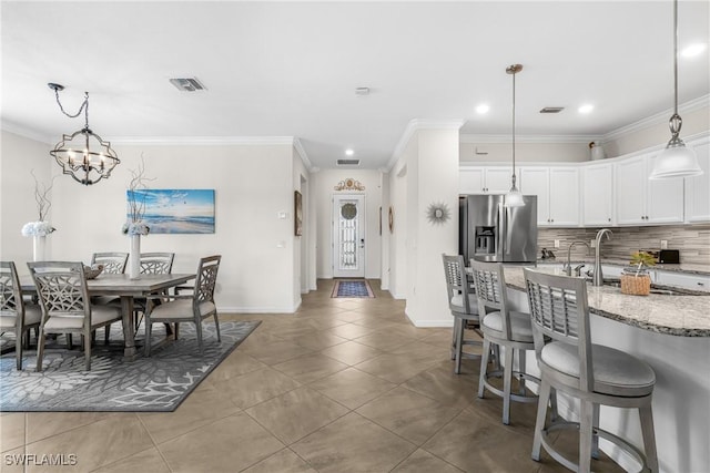 tiled dining area with a chandelier and crown molding