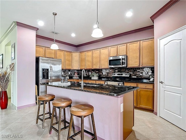 kitchen featuring a center island with sink, stainless steel appliances, decorative light fixtures, and ornamental molding