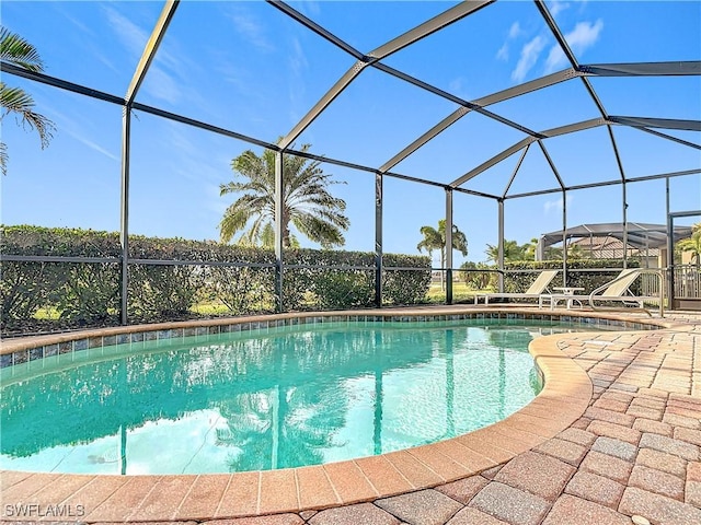 view of pool with glass enclosure and a patio area