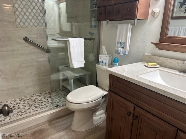 bathroom featuring toilet, a shower stall, wood finished floors, and vanity