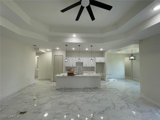 kitchen with white cabinetry, hanging light fixtures, and an island with sink