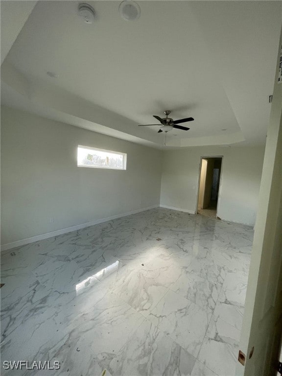 spare room featuring ceiling fan and a raised ceiling