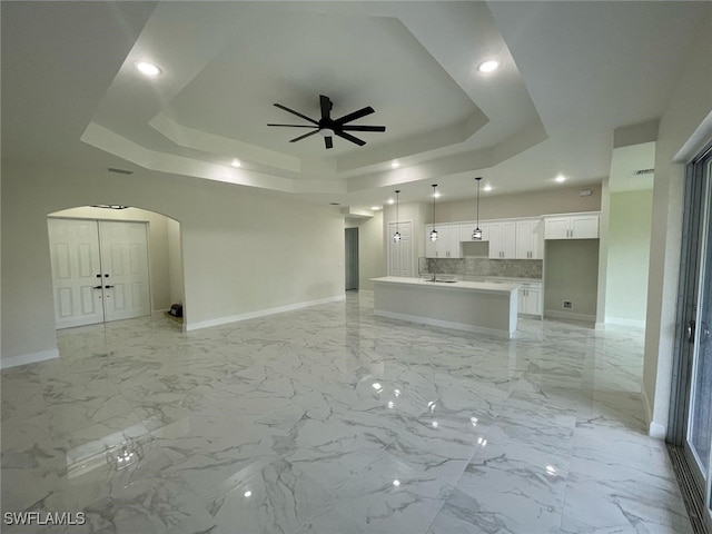 6024 Joplin Ave, Fort Myers, FL 33905 - unfurnished living room featuring a tray ceiling, baseboards, marble finish floor, arched walkways, and ceiling fan