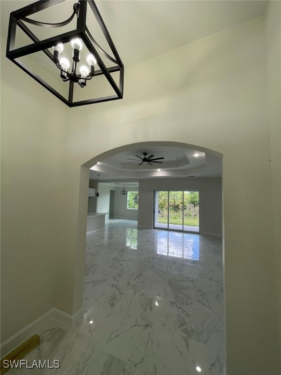 6024 Joplin Ave, Fort Myers, FL 33905 - interior space featuring baseboards, marble finish floor, arched walkways, ceiling fan with notable chandelier, and a tray ceiling