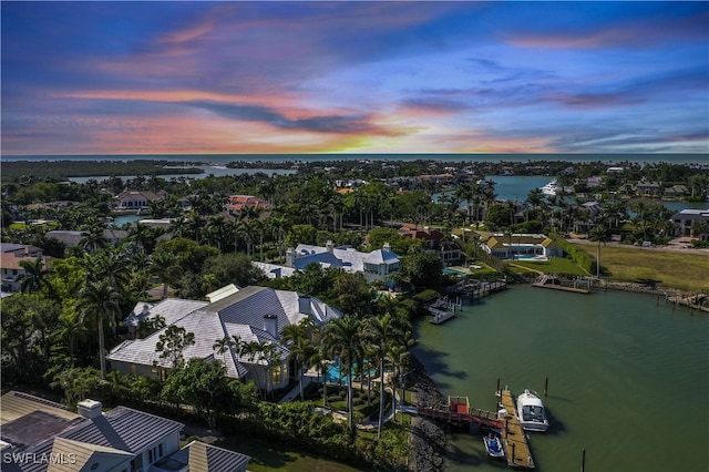 aerial view at dusk featuring a water view