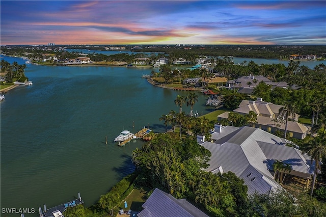 aerial view at dusk featuring a water view