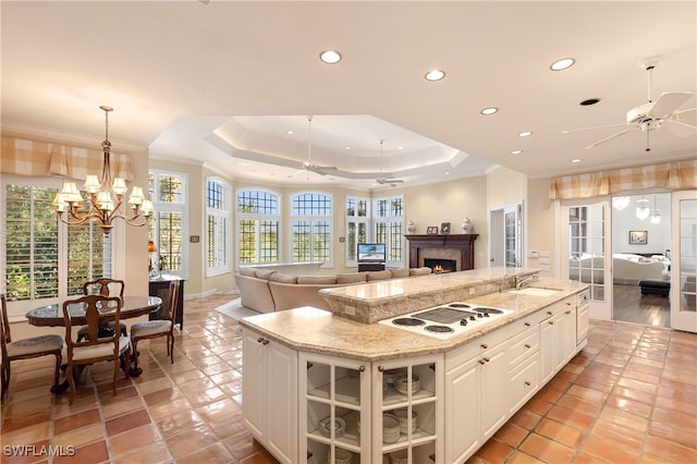 kitchen with white cabinetry, hanging light fixtures, a healthy amount of sunlight, and an island with sink